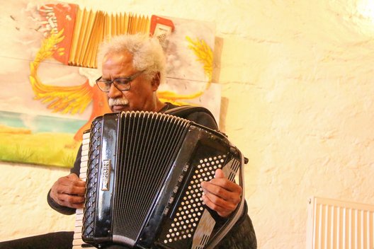 Der aus Panama stammende Paderborner Akkordeonist René Madrid musiziert vor einem Akkordeon-Gemälde von Gennadi Isaak.